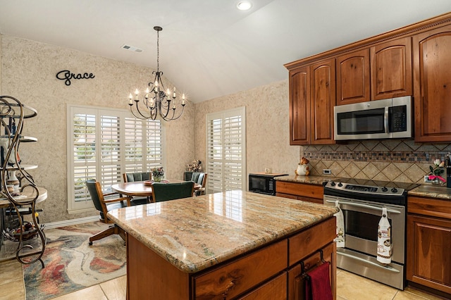 kitchen with light stone counters, visible vents, vaulted ceiling, appliances with stainless steel finishes, and a center island