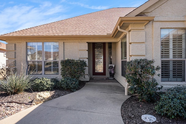 property entrance featuring a shingled roof and stucco siding