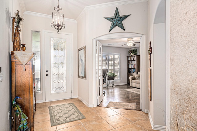 foyer featuring arched walkways, light tile patterned floors, baseboards, ornamental molding, and an inviting chandelier