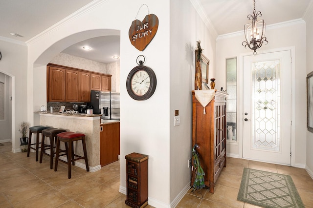 kitchen with light countertops, stainless steel fridge, crown molding, and a kitchen breakfast bar