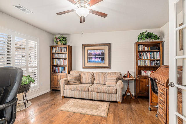 home office with ceiling fan, hardwood / wood-style flooring, visible vents, and baseboards