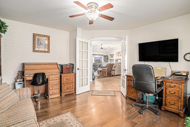 office with a ceiling fan, arched walkways, french doors, and wood finished floors