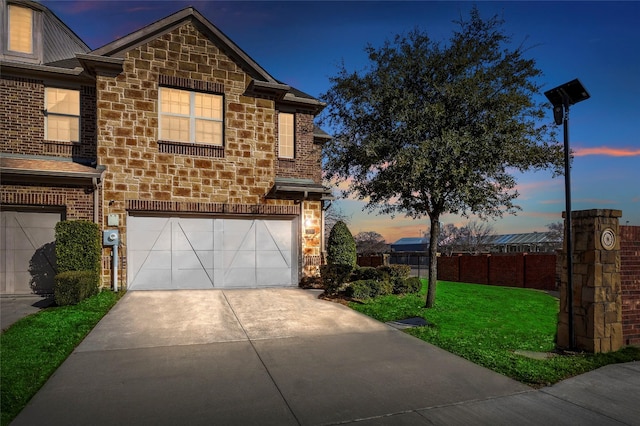 traditional home featuring stone siding, fence, concrete driveway, and an attached garage