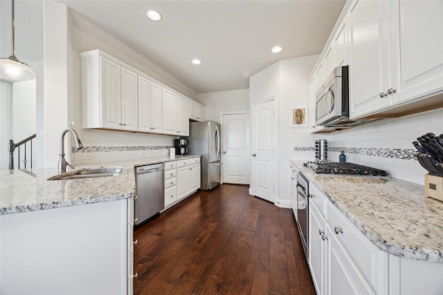 kitchen featuring dark wood finished floors, light stone countertops, stainless steel appliances, white cabinetry, and a sink