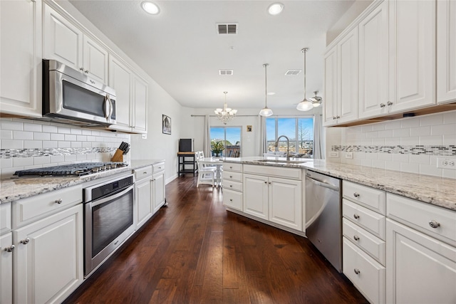 kitchen with a peninsula, a sink, visible vents, white cabinets, and appliances with stainless steel finishes