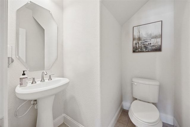 bathroom featuring lofted ceiling, baseboards, toilet, and tile patterned floors