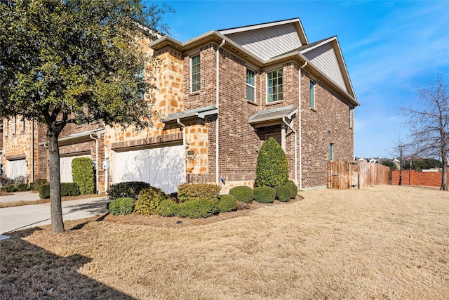 view of front of house featuring an attached garage, brick siding, fence, driveway, and stone siding