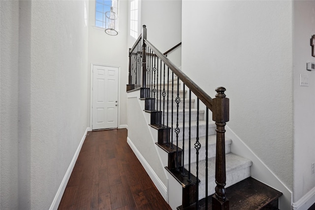 staircase with a high ceiling, baseboards, and hardwood / wood-style flooring