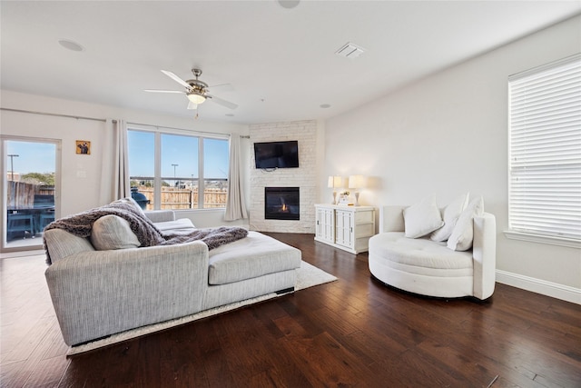 living area featuring ceiling fan, a fireplace, baseboards, and wood finished floors