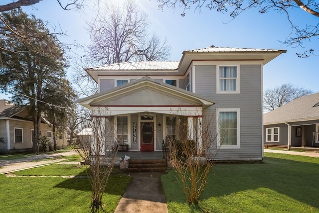 view of front of property featuring covered porch, metal roof, and a front yard