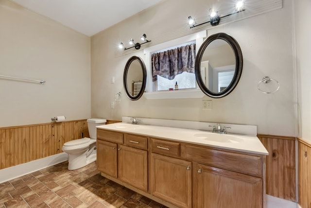 full bath with a wainscoted wall, a sink, and wood walls