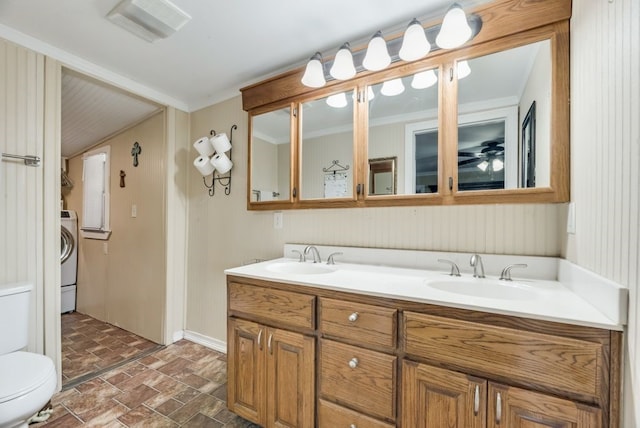 full bathroom with double vanity, washer / dryer, a sink, and toilet