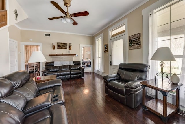 living room featuring hardwood / wood-style flooring, ceiling fan, visible vents, and ornamental molding