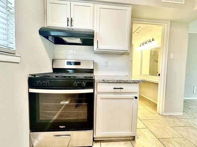 kitchen with under cabinet range hood, stainless steel gas range oven, white cabinetry, and tasteful backsplash