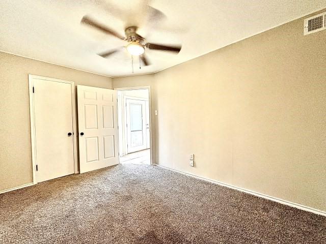 unfurnished bedroom with carpet floors, visible vents, and a ceiling fan