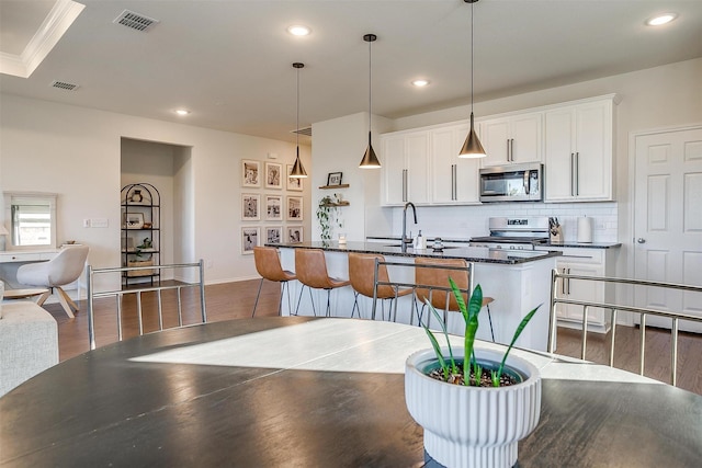 kitchen featuring tasteful backsplash, visible vents, dark wood-style floors, stainless steel appliances, and a sink