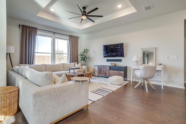 living area featuring visible vents, a ceiling fan, ornamental molding, wood finished floors, and a tray ceiling