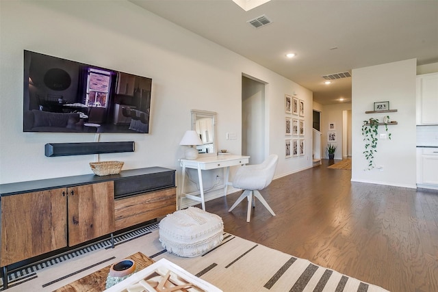 living area with visible vents, baseboards, and wood finished floors