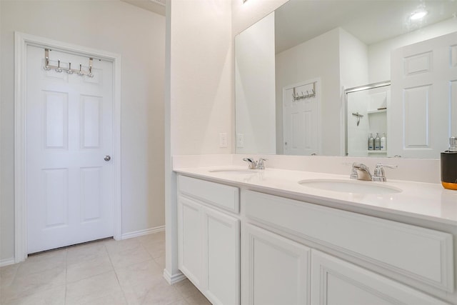 full bath featuring a shower stall, double vanity, a sink, and tile patterned floors