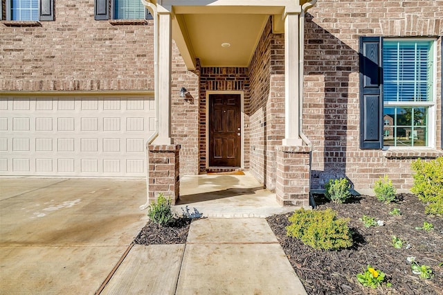 view of exterior entry with driveway and brick siding