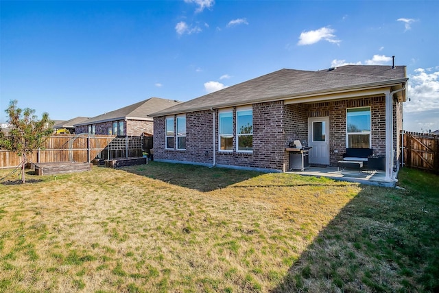 rear view of property featuring a yard, brick siding, a patio, and a fenced backyard