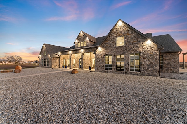 french country inspired facade featuring stone siding and roof with shingles