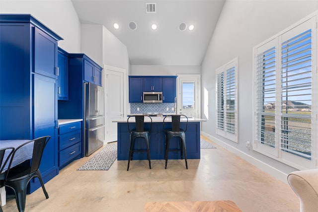 kitchen with visible vents, appliances with stainless steel finishes, a kitchen island with sink, concrete floors, and a kitchen breakfast bar