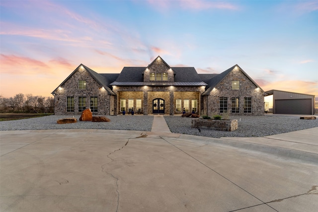 french provincial home featuring a garage, metal roof, french doors, and a standing seam roof