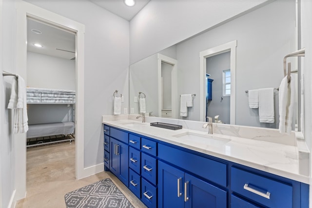 bathroom with double vanity, concrete floors, a sink, and baseboards