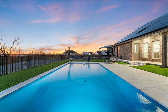 pool at dusk featuring a fenced in pool, a fenced backyard, a yard, and a patio