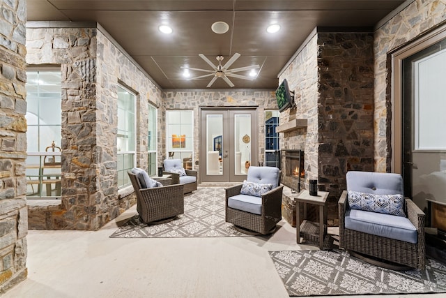 view of patio featuring ceiling fan, an outdoor stone fireplace, and french doors