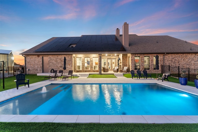 pool at dusk featuring a patio, a lawn, fence, and a fenced in pool