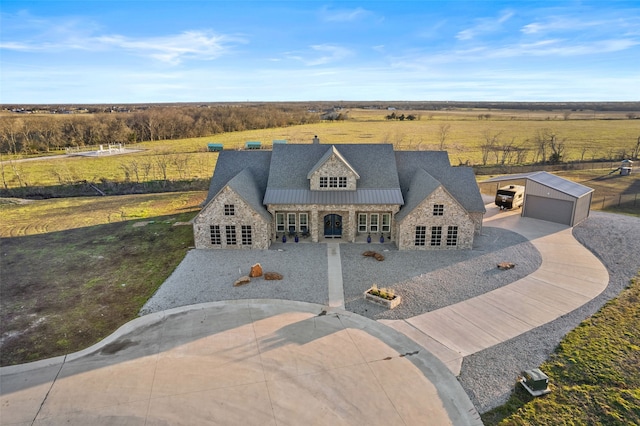 view of front of property with driveway, stone siding, metal roof, a standing seam roof, and an outdoor structure