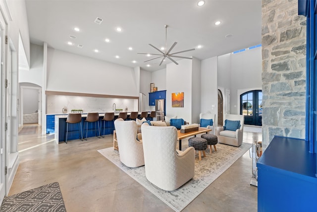 living area featuring arched walkways, a high ceiling, concrete floors, and recessed lighting