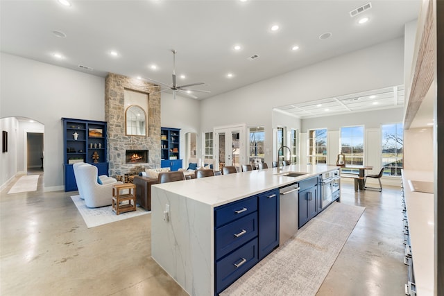 kitchen featuring finished concrete flooring, visible vents, arched walkways, a sink, and stainless steel dishwasher