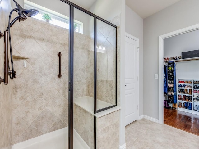 bathroom featuring a shower stall, a spacious closet, and tile patterned floors