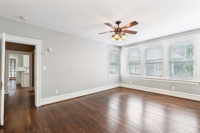 spare room with ceiling fan, wood finished floors, visible vents, and baseboards