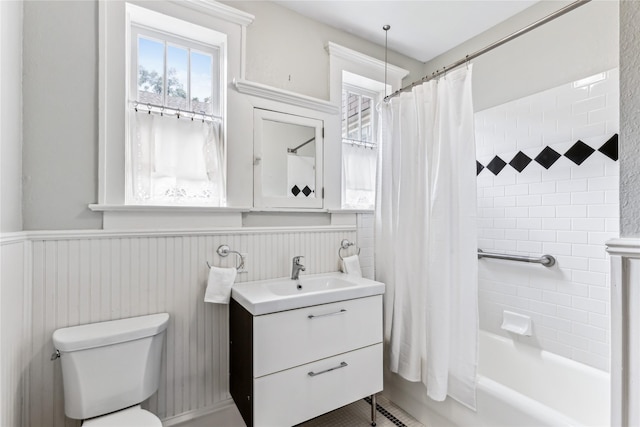 full bathroom with a wainscoted wall, vanity, shower / bath combo with shower curtain, and toilet