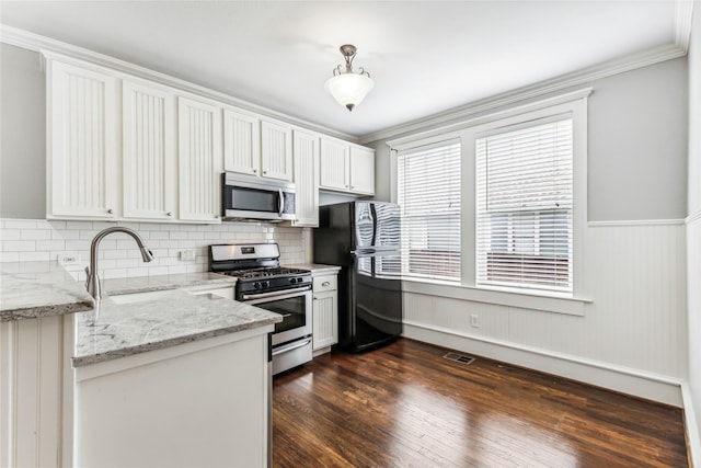 kitchen featuring dark wood-style floors, stainless steel appliances, backsplash, a sink, and light stone countertops