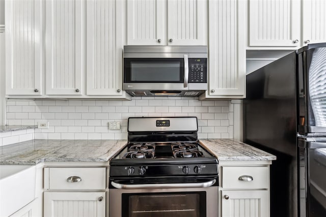 kitchen featuring light stone counters, appliances with stainless steel finishes, white cabinetry, and tasteful backsplash