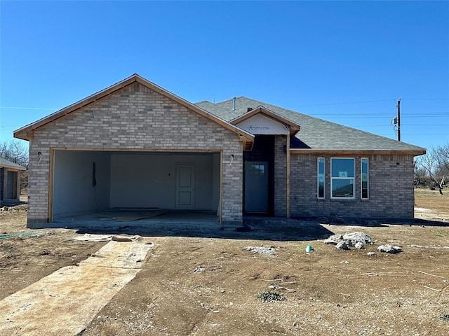 view of front of home featuring a garage, roof with shingles, and brick siding