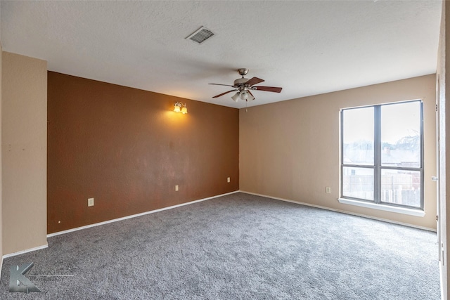 carpeted empty room with a ceiling fan, baseboards, visible vents, and a textured ceiling