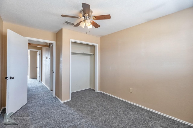 unfurnished bedroom with a closet, visible vents, dark carpet, ceiling fan, and a textured ceiling