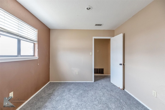 spare room with carpet, visible vents, and baseboards