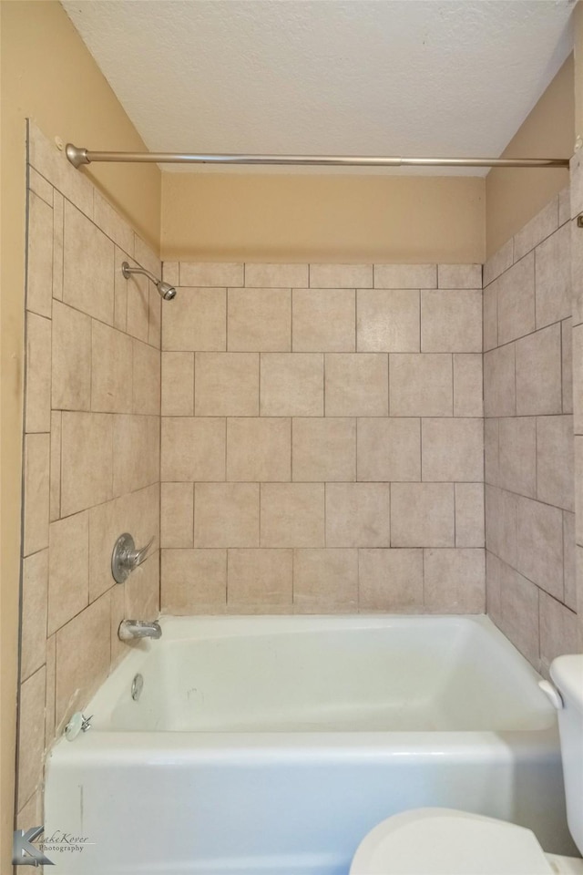 bathroom featuring toilet,  shower combination, and a textured ceiling