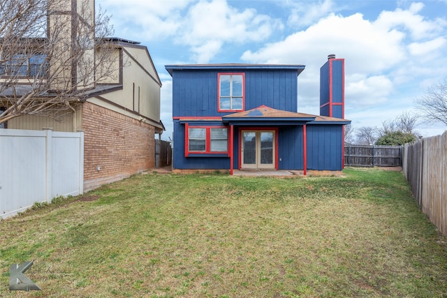 rear view of house featuring a fenced backyard, a lawn, and french doors