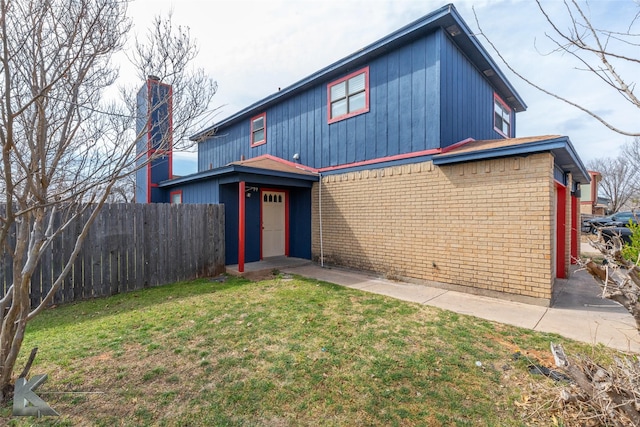 traditional-style home with brick siding, a front yard, and fence