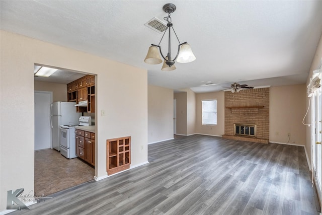 unfurnished living room with baseboards, visible vents, wood finished floors, a fireplace, and ceiling fan with notable chandelier