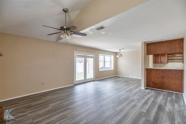 unfurnished living room featuring dark wood finished floors, visible vents, vaulted ceiling, baseboards, and ceiling fan with notable chandelier