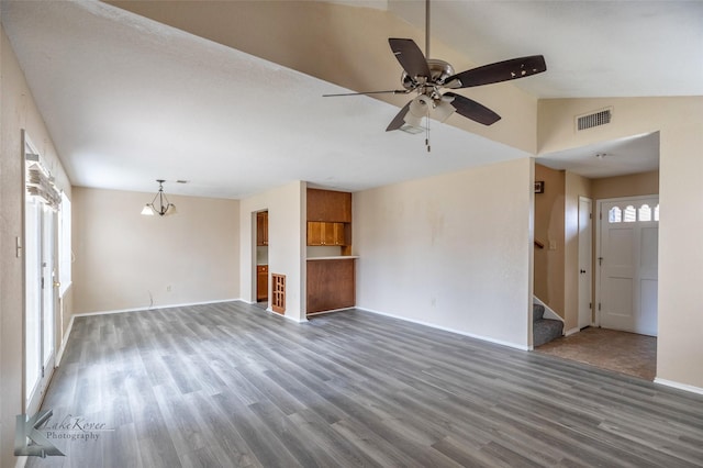 unfurnished living room with lofted ceiling, ceiling fan with notable chandelier, wood finished floors, visible vents, and stairs